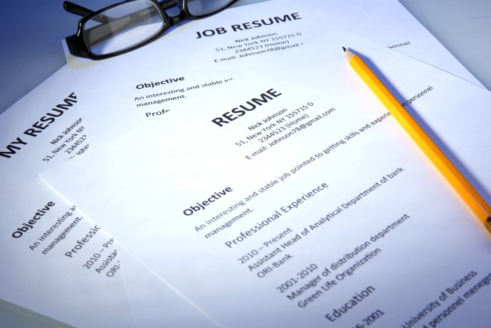 Closeup of resume with glasses and pencil on blue background